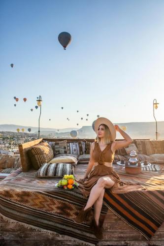 a woman in a dress and a hat sitting on a beach at Charming Cave Hotel in Goreme