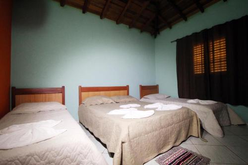 two beds in a room with towels on them at Pousada Oasis in Olímpia