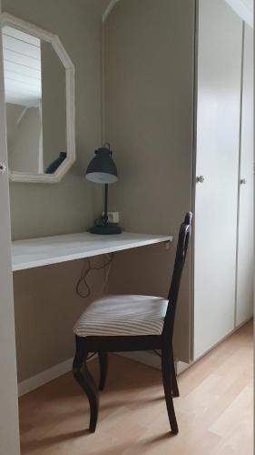 a desk with a chair and a lamp on a shelf at Epokgården in Öregrund