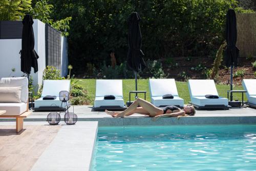 a woman laying on the edge of a swimming pool at Physis Villas - Metal & Wood in Pigi