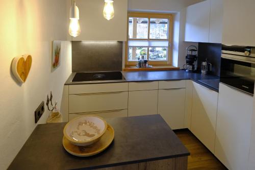 a kitchen with white cabinets and a bowl on a counter at Ferienwohnung Mitteldorf in Oberammergau