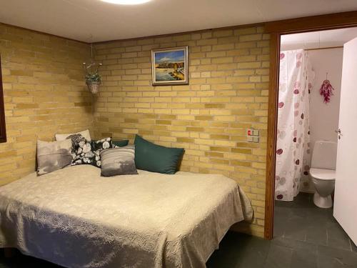 um quarto com uma cama e uma parede de tijolos em Eskærhus på Tåsinge, tæt på Svendborg - Afdeling med egen indgang em Troense