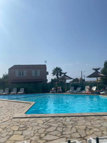 une piscine avec des chaises et une maison en arrière-plan dans l'établissement Les marines d'helios, à Le Castellas