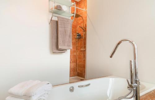 uma casa de banho com uma banheira e um chuveiro com toalhas em Maison Rose em Ypres
