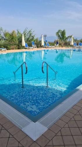 einen großen Pool mit blauem Wasser und Stühlen in der Unterkunft Residence FioriBello MariGio&Paolo in Longbardi