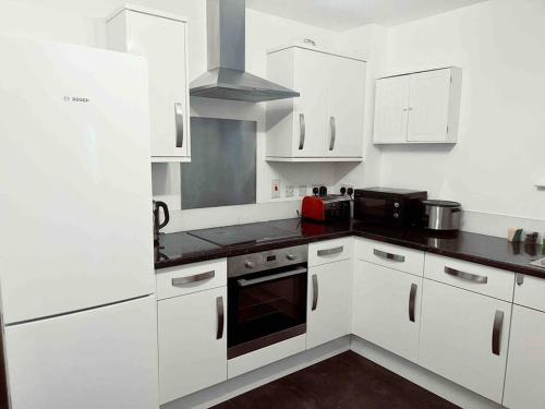 a kitchen with white cabinets and a black counter top at 2 bedrooms flat @ London Sutton Station Zone 5 in Sutton