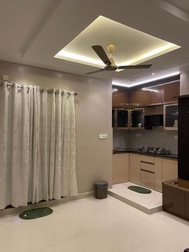 a living room with a ceiling fan and a kitchen at AVVAIRAM SERVICE APARTMENT G8 in Chennai