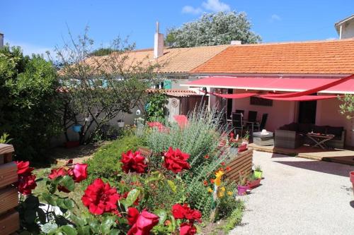 un jardín con flores rojas frente a una casa en La Cotinière, studio avec cuisine 50 m de la plage en La Cotinière