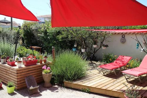 un patio con sombrilla roja, sillas y plantas en La Cotinière, studio avec cuisine 50 m de la plage en La Cotinière