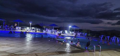 ein Swimmingpool mit Menschen darin in der Nacht in der Unterkunft Apartamento Porto Real Suites in Mangaratiba