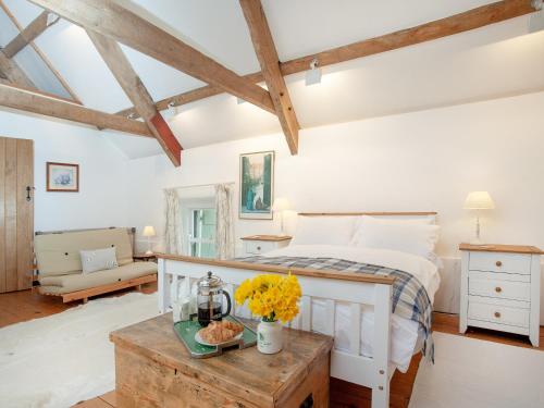 Un dormitorio con una cama y una mesa con flores. en The Tithe Barn en Stoke Canon