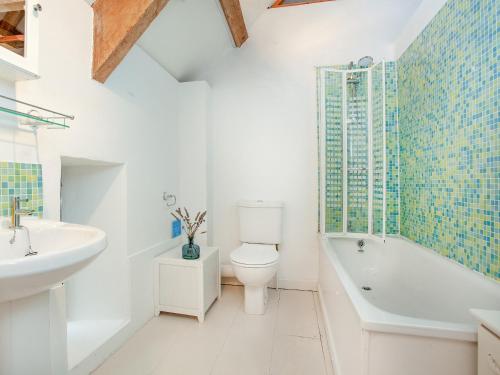 a bathroom with a toilet and a bath tub and a sink at The Tithe Barn in Stoke Canon