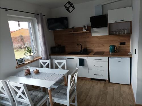 uma cozinha com uma mesa branca e cadeiras num quarto em Domek nad potokiem em Grywałd