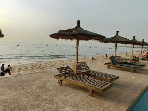 a group of beach chairs and umbrellas on a beach at CASA COCO II in Nianing