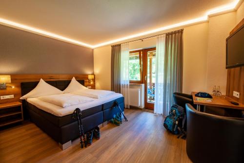 Schlafzimmer mit einem Bett, einem Schreibtisch und einem TV in der Unterkunft Hotel Landgasthof Oberschnorrhof in Dammbach