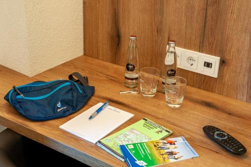 a table with a bag and a book and a remote control at Hotel Landgasthof Oberschnorrhof in Dammbach