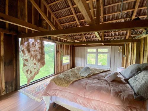 a large bed in a room with a large window at Celeiro Guarapuava, 4 quartos, Paz e Tranquilidade in Guarapuava