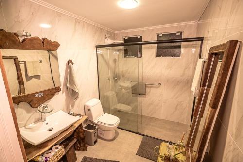 a bathroom with a shower and a toilet and a sink at Celeiro Guarapuava, 4 quartos, Paz e Tranquilidade in Guarapuava
