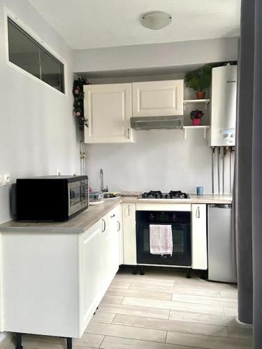 eine Küche mit weißen Schränken und einer schwarzen Mikrowelle in der Unterkunft Apartment in the heart of Chinatown, Paris in Paris
