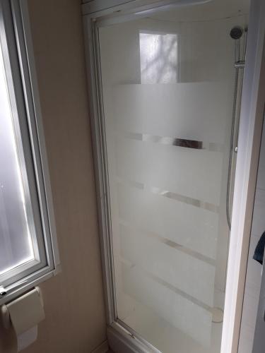 y baño con ducha de cristal y ventana. en MOBILHOME agréable sans draps ni serviettes, en Port-la-Nouvelle