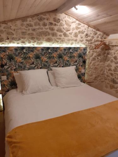 1 dormitorio con cama blanca y pared de piedra en Le gîte de la cabane de l'oiseau, en Couze-et-Saint-Front