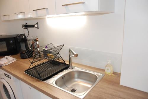 a kitchen sink with a dish drying rack next to it at Suite avec terrasse, Nancy Thermal, parc Ste Marie in Nancy