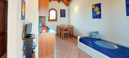 a room with a bed and a kitchen with a television at Appartamento Residenziale Bilocale Citai San Teodoro in San Teodoro