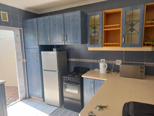een keuken met blauwe kasten en een witte koelkast bij Mia Haven 2 in Scottburgh
