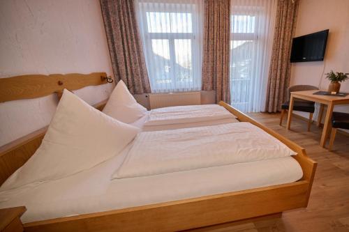a bedroom with a large bed with white sheets at Gasthof Oberwirt in Ramsau