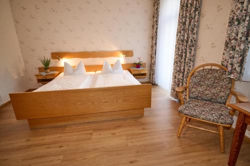 a bedroom with a large bed and a chair at Gasthof Oberwirt in Ramsau