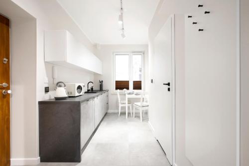 a kitchen with white cabinets and a black counter top at Rakowicka 71 Partnerapart in Krakow