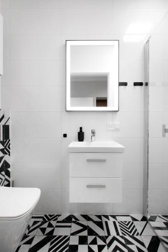 a white bathroom with a sink and a mirror at Rakowicka 71 Partnerapart in Krakow
