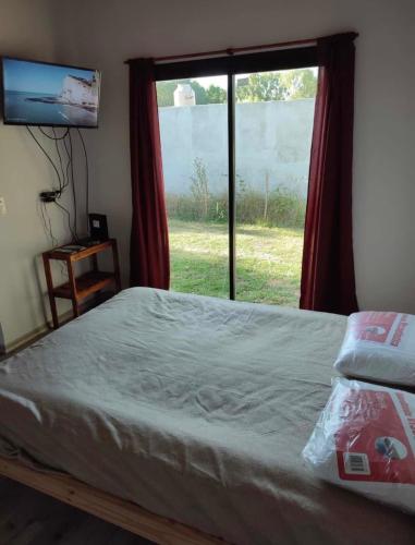 1 dormitorio con cama y ventana grande en Cabaña en Chascomús cercana a la estación en Chascomús