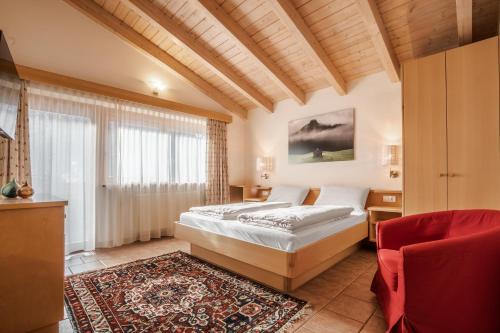 a bedroom with a bed and a red chair at Appartamenti Residence Ada in San Cassiano