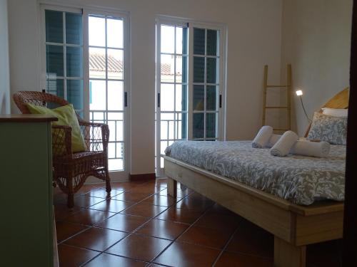 a bedroom with a bed and two chairs and windows at BRIGHT AMBIENCE by Stay in Alentejo in Vila Nova de Milfontes