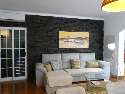 a living room with a white couch and a brick wall at BRIGHT AMBIENCE by Stay in Alentejo in Vila Nova de Milfontes