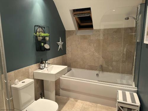 a bathroom with a toilet and a tub and a sink at Ocean Retreat in Filey