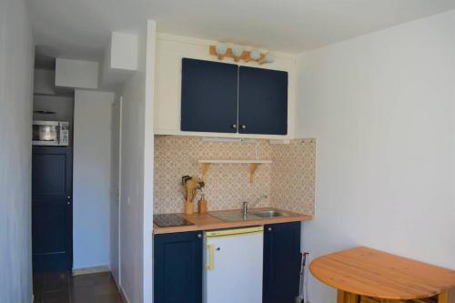 uma cozinha com armários azuis e uma mesa de madeira em Studio de 18m² rénové en 2023. em Le Grau-du-Roi