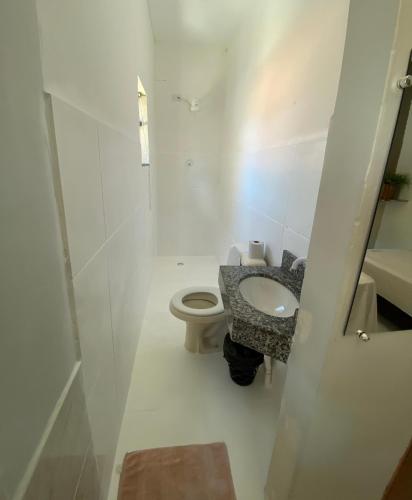 a white bathroom with a toilet and a sink at Hotel Dallas Ipiranga in Bom Jesus da Lapa