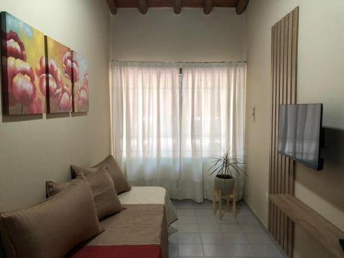 1 dormitorio con 1 cama, TV y ventana en Apartamentos María en San Rafael