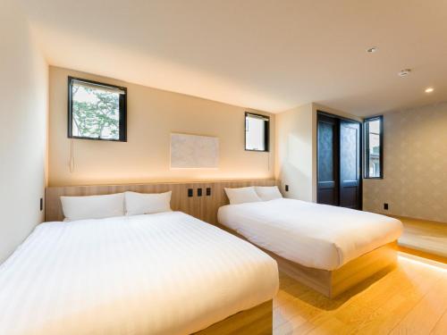 two beds in a room with two windows at Rakuten STAY VILLA Kamogawa Building B with Terrace and sauna Capacity of 12 persons in Kamogawa
