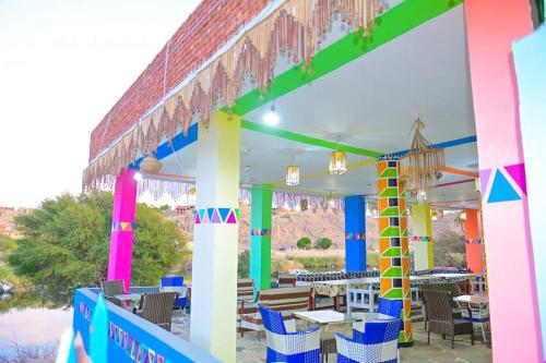 a brightly colored restaurant with tables and chairs at Sehel Nubian House in Naj‘ al Maḩaţţah