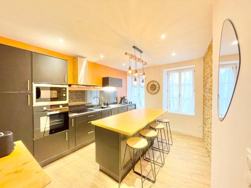 une cuisine équipée d'appareils en acier inoxydable et d'un bar avec tabourets dans l'établissement LE SALLÉ - Confort - Wifi - Centre Historique - Entrée Autonome, à Quimper