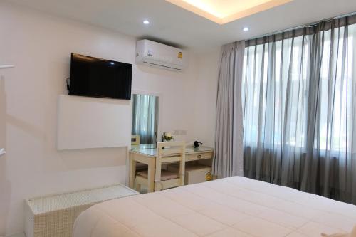 a bedroom with a bed and a desk and a television at Baanpoon Apartment in Chaweng