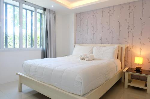 a bedroom with a white bed with a stuffed animal on it at Baanpoon Apartment in Chaweng