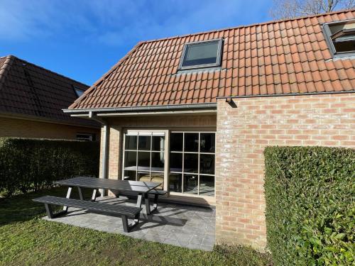 een picknicktafel voor een bakstenen gebouw bij Casa Vista Verde in De Panne