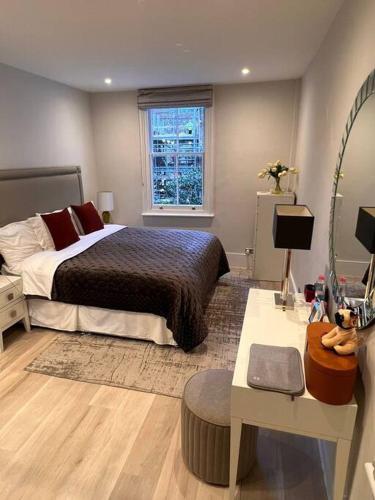 倫敦的住宿－One bedroom flat in Chelsea，一间卧室配有一张床、一张桌子和一面镜子