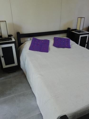 Una cama con dos almohadas moradas encima. en Casa en Arachania - La Paloma, en La Paloma