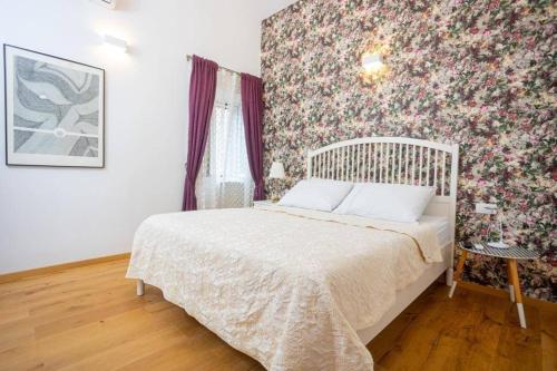 - une chambre avec un lit et un papier peint floral dans l'établissement Apartment Oskar, à Supetar