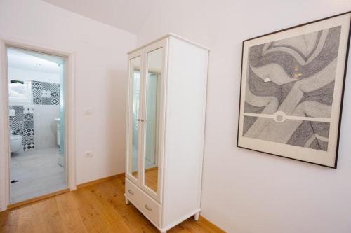 una camera bianca con specchio e una foto appesa a un muro di Apartment Oskar a Supetar (San Pietro di Brazza)
